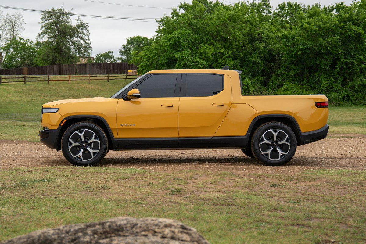 Yellow Rivian R1T electric truck with black trim and distinctive multi-spoke rims.