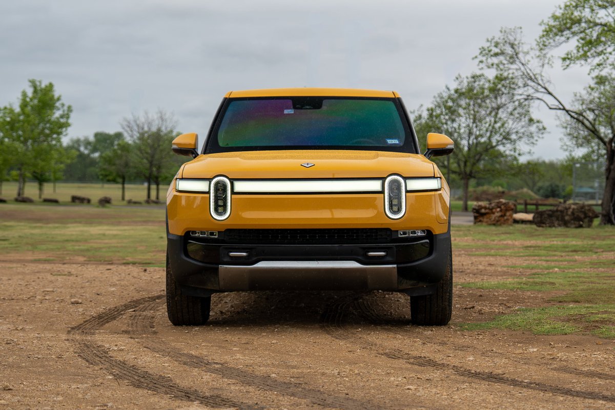 Yellow 2022 Rivian R1T electric truck with distinctive LED light bar and vertical headlights.