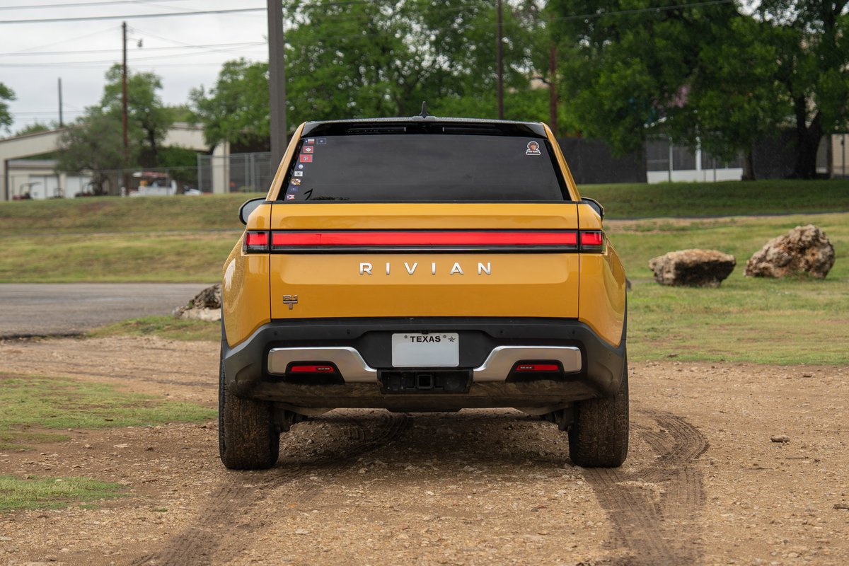 Yellow 2022 Rivian R1T rear view with Texas license plate and black trim.