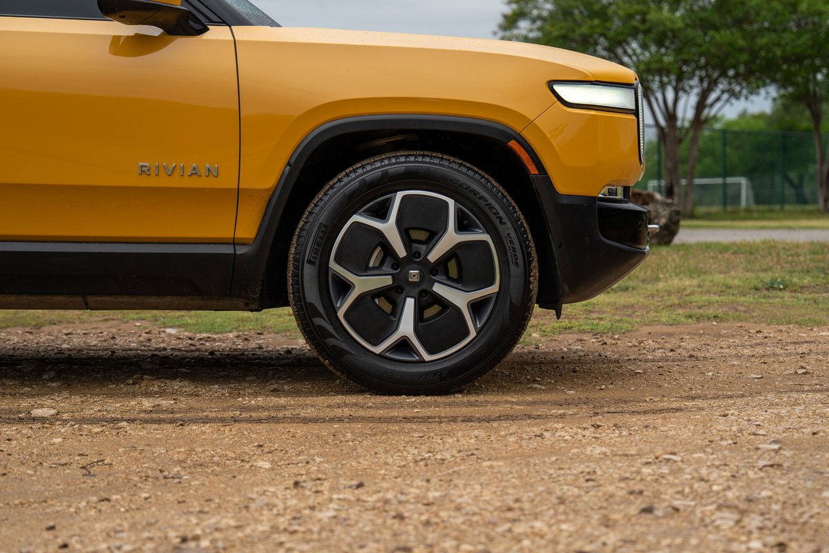 Yellow Rivian R1T front fender and alloy rims on dirt road.