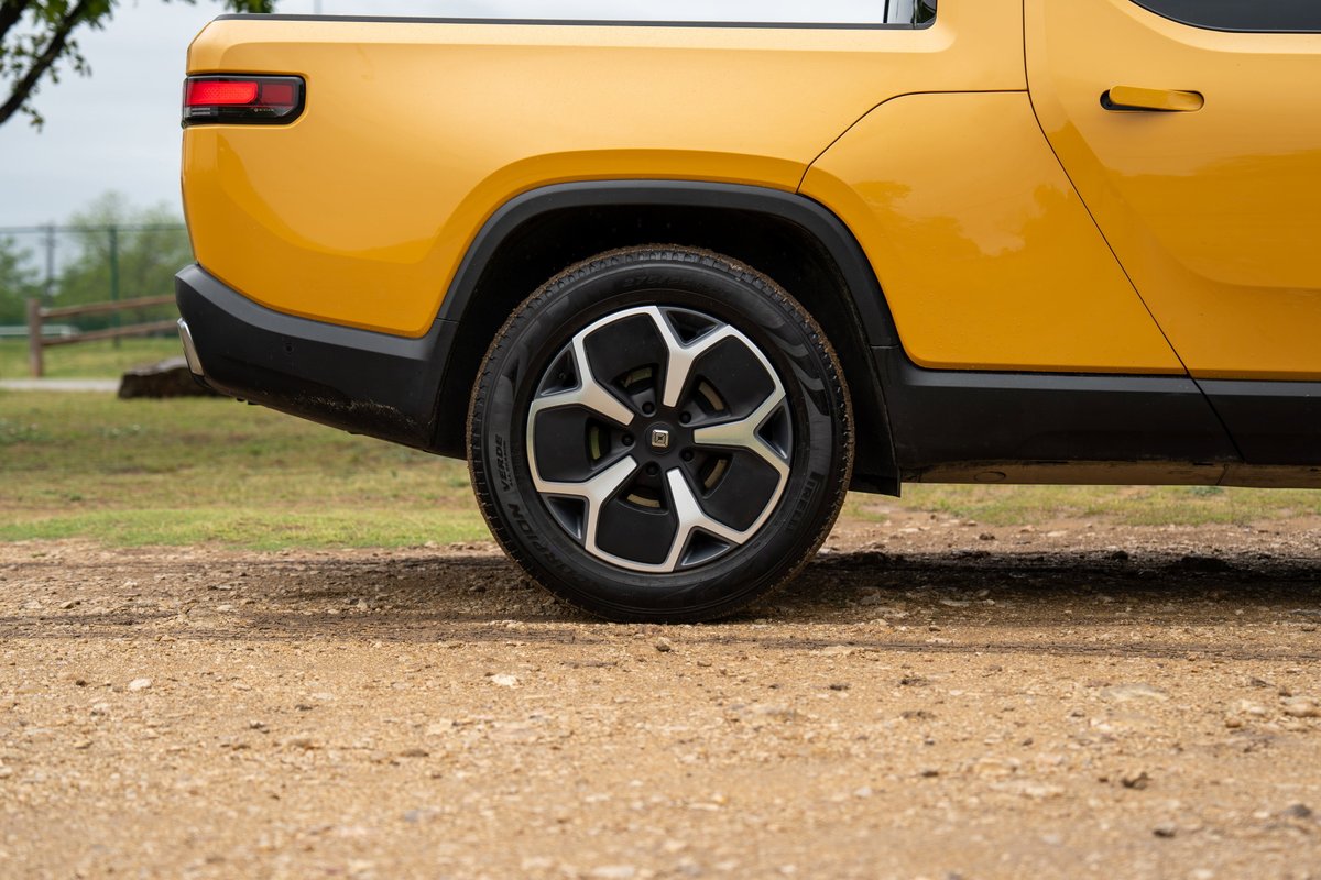Yellow Rivian R1T pickup truck, close-up of the rear wheel with a black and silver rim.