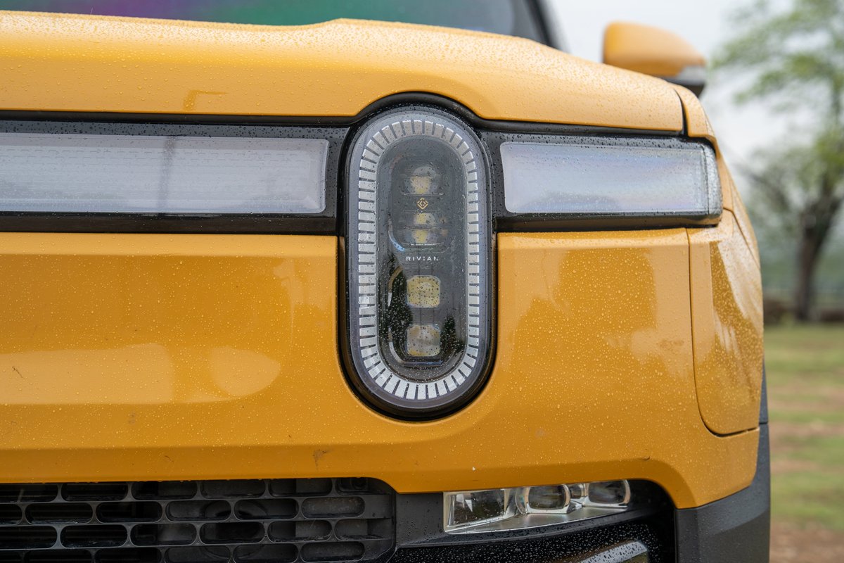Yellow 2022 Rivian R1T pickup truck's front headlight detail.
