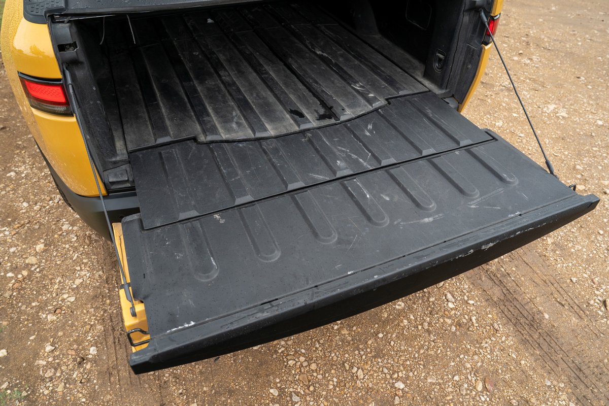 Yellow Rivian R1T tailgate lowered, revealing the ribbed bed liner.