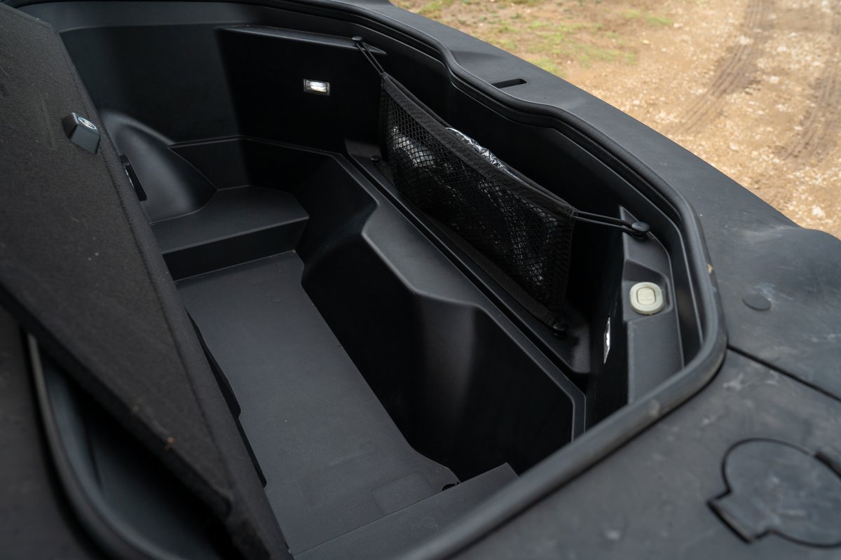 Rivian R1T electric pickup truck frunk interior with storage net and lighting.