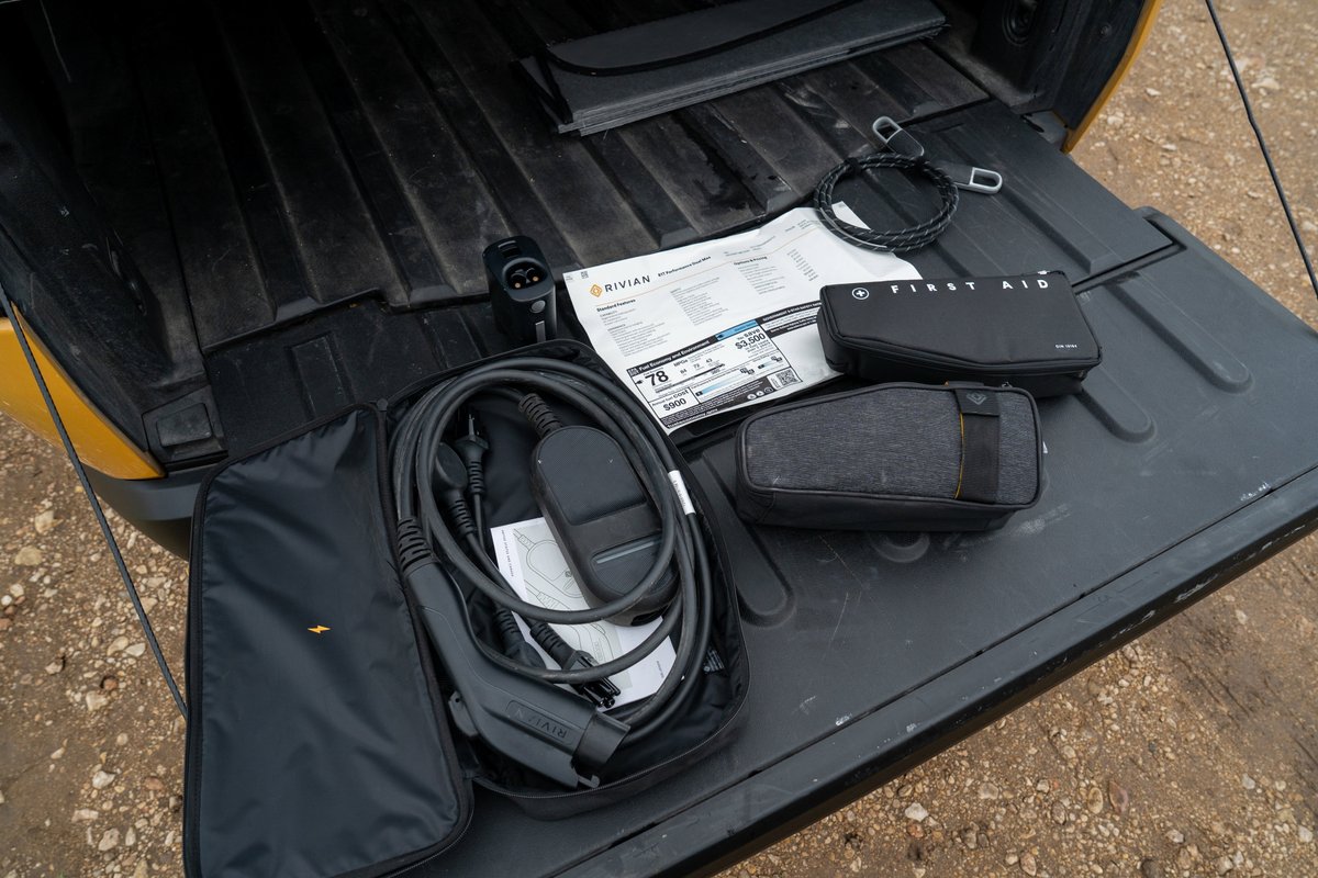 Rivian R1T charging cable and first aid kit in yellow pickup truck bed.