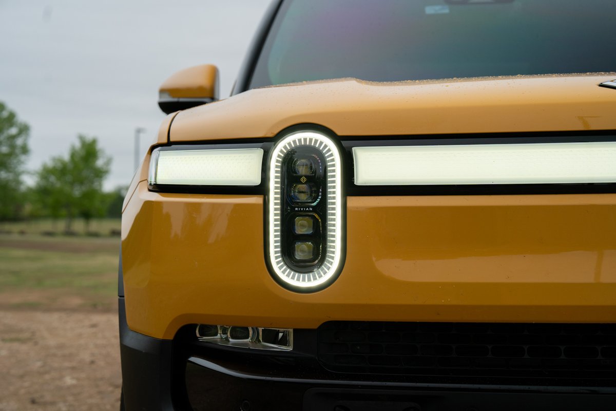 Close up of a yellow 2022 Rivian R1T electric truck's LED headlights and front grille.