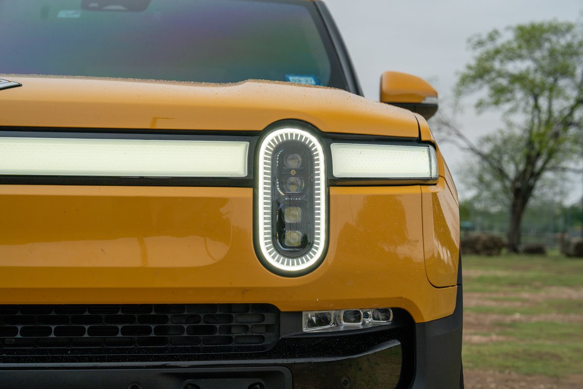 Front view of a yellow 2022 Rivian R1T electric truck with distinctive LED headlights and daytime running lights.