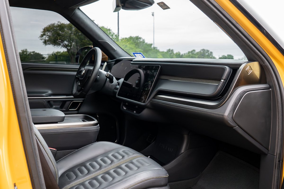Interior of a yellow 2022 Rivian R1T showing the dashboard, steering wheel, and driver's seat.