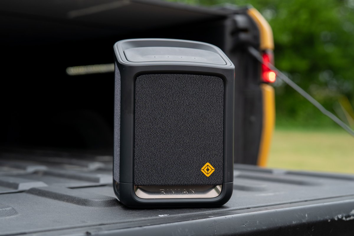 Yellow Rivian R1T tailgate with a Rivian speaker accessory.