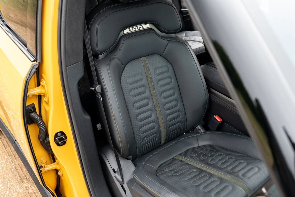 Yellow 2022 Rivian R1T driver's seat with perforated leather and olive green trim.