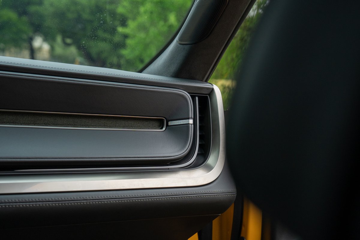 Close-up of a yellow Rivian R1T's interior, showing a sleek dashboard air vent with silver trim.