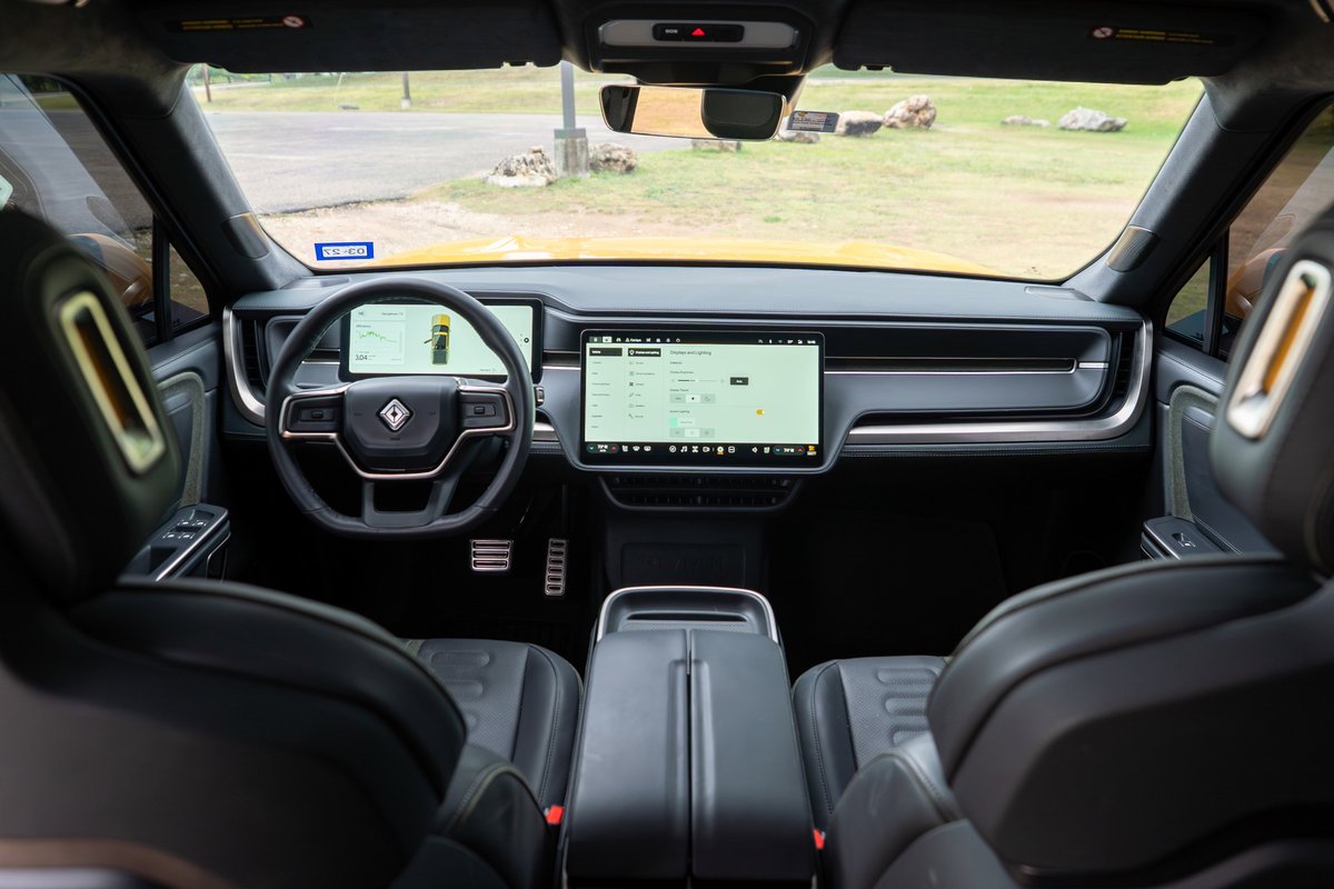 2022 Rivian R1T interior: Minimalist dash with large touchscreens, digital cluster, and luxurious black leather trim.