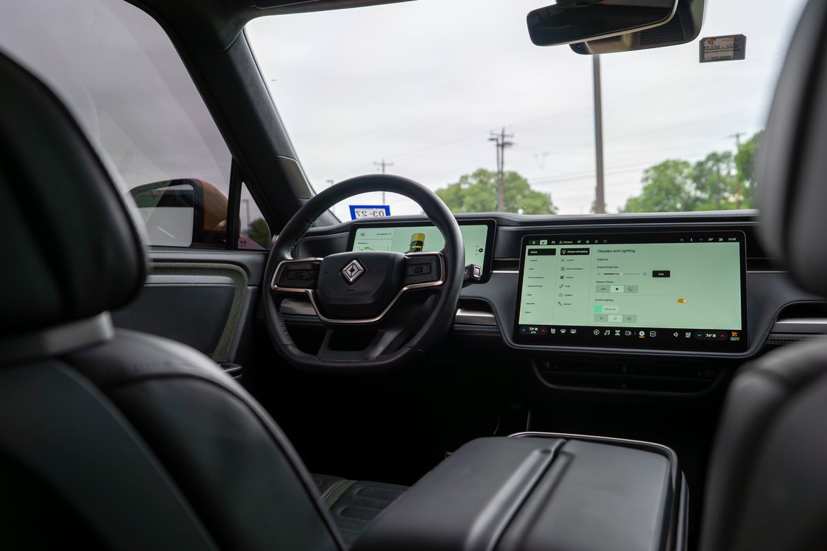 Interior of a yellow 2022 Rivian R1T showing the dashboard, steering wheel, and large infotainment screen.