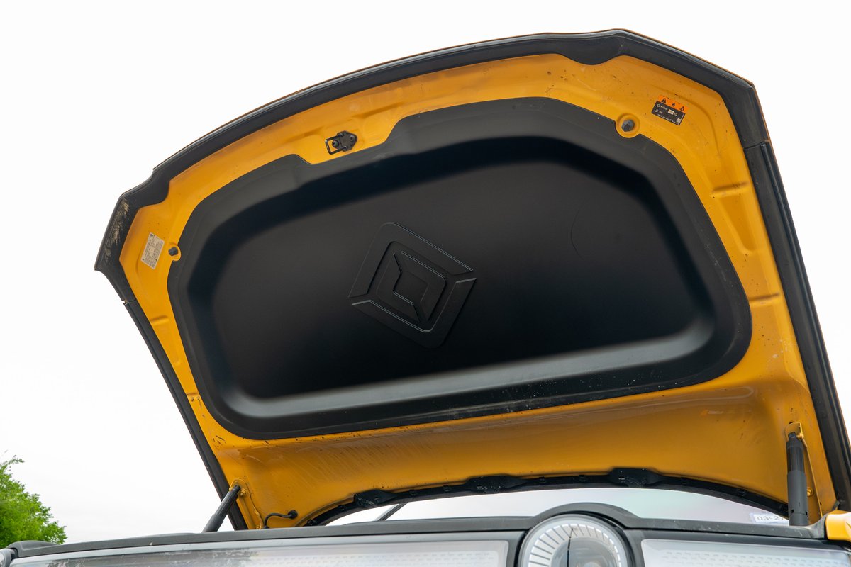 Open hood of a yellow Rivian R1T, showing insulation and latch mechanism.
