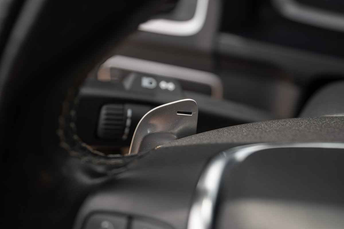 Close-up of a silver paddle shifter on a black leather steering wheel of a 2015 Volvo V60 R-Design Polestar.