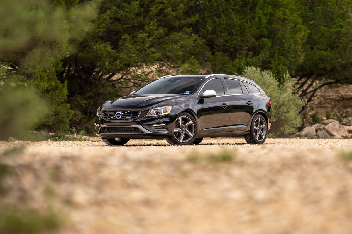 Black 2015 Volvo V60 R-Design Polestar with silver rims parked on dirt road.