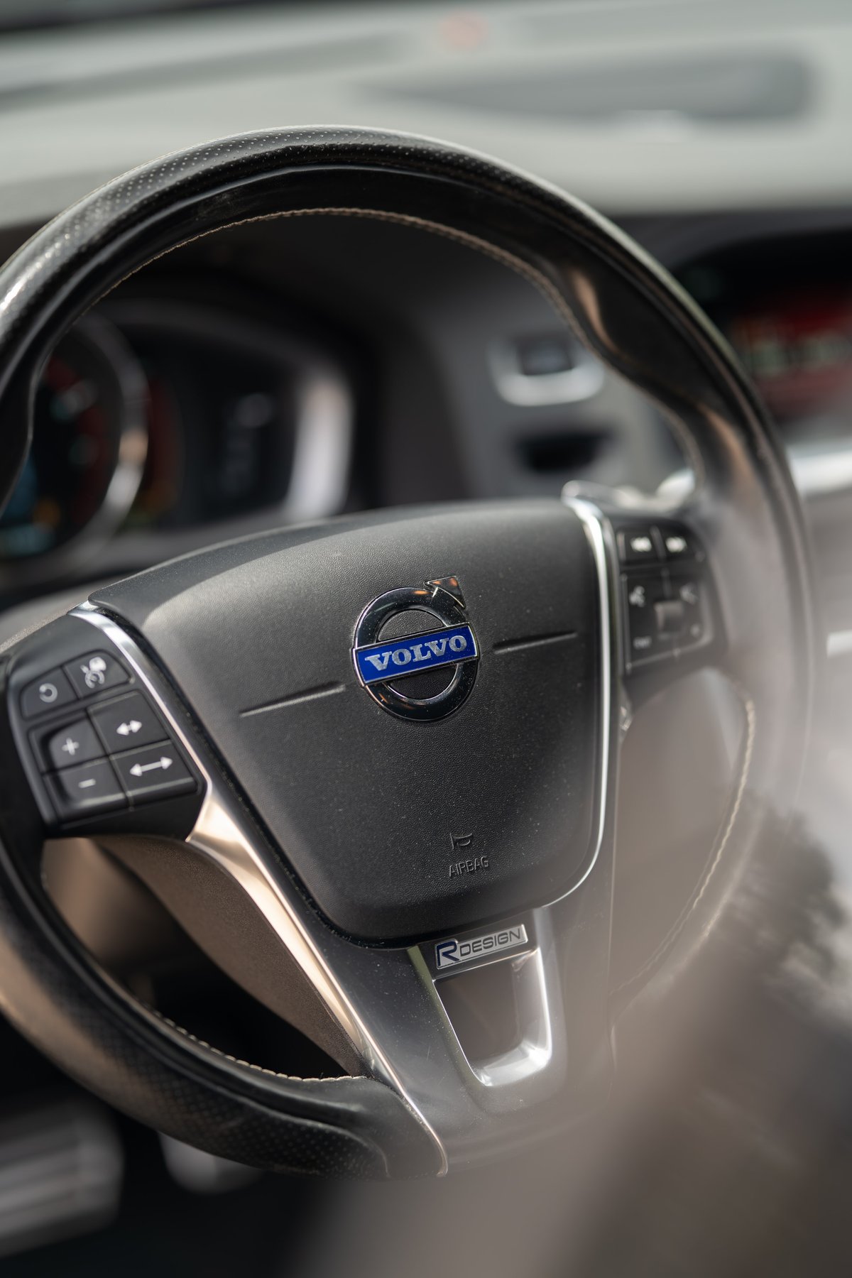 Close-up of a black Volvo V60 R-Design steering wheel with R-Design badge and Volvo logo.