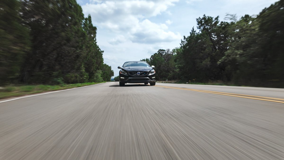 Black 2015 Volvo V60 R-Design Polestar speeding on a rural road.