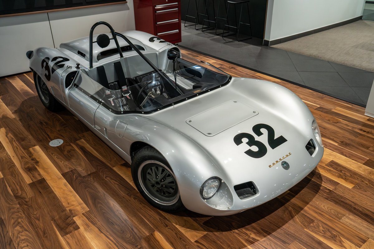 Silver 1964 Elva Porsche 4-Cam race car with black number 32 livery and dark rims.