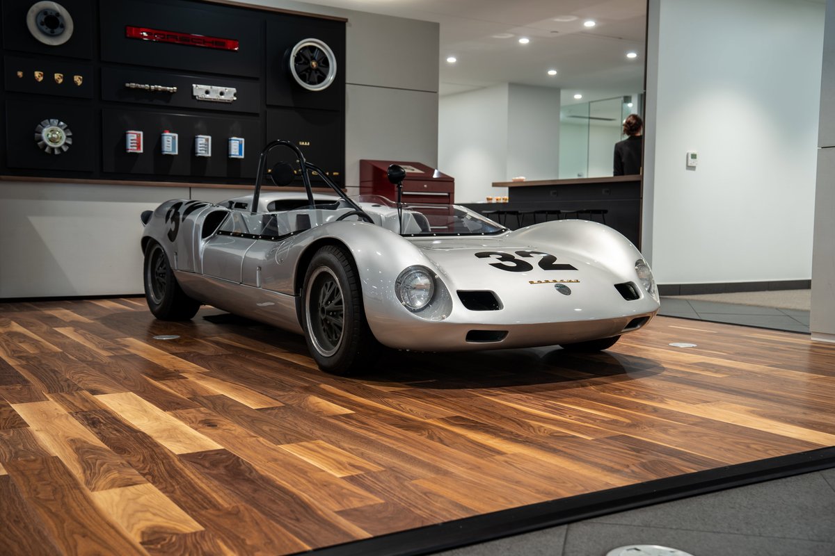 Silver 1964 Elva Porsche 4-Cam race car with black racing livery and wire-spoke rims.