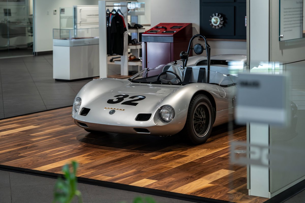 Silver 1964 Elva Porsche 4-Cam race car with #32 livery and black rims.