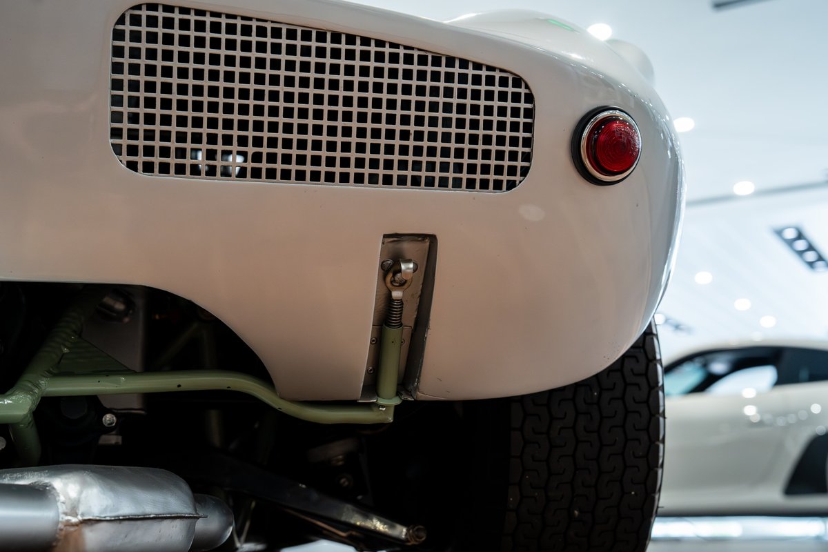 Rear view of a white 1964 Elva Porsche 4-cam with a red taillight and grille.