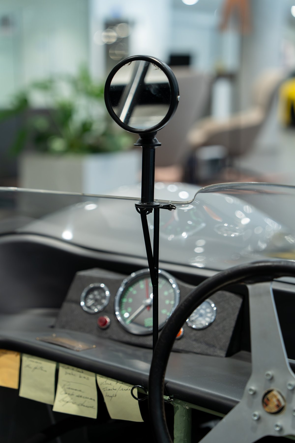 1964 Elva Porsche 4-Cam cockpit with circular mirror, gauges, and aluminum steering wheel.