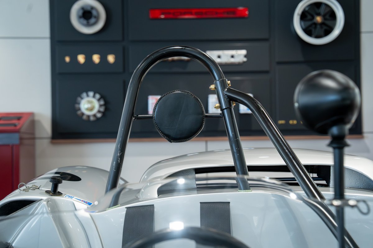 Close-up of a vintage silver Elva Porsche 4-cam race car with a roll bar and black trim.