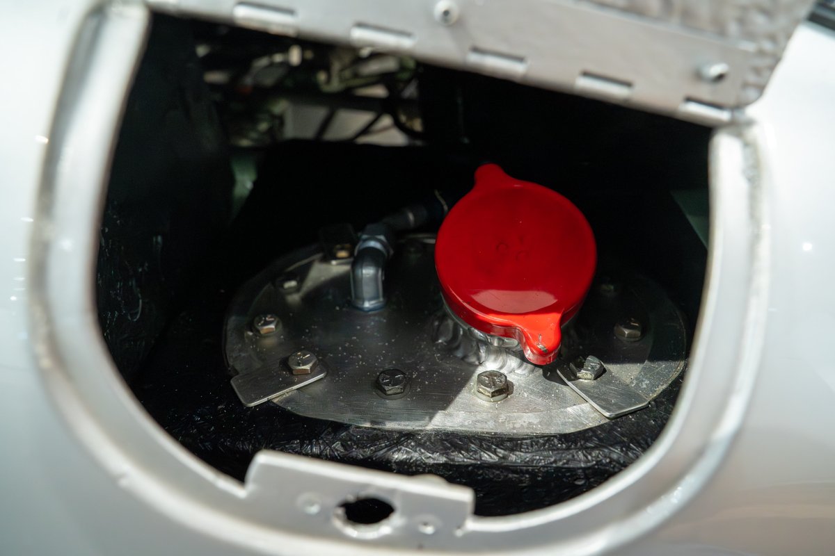 Close-up of the 1964 Elva Porsche 4-Cam's red fuel filler cap and silver mounting plate.