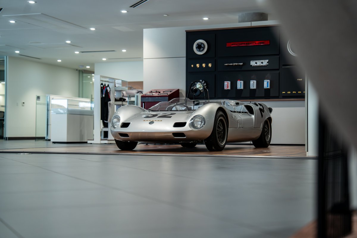 A silver 1964 Elva Porsche 4-Cam race car with black rims and racing livery.