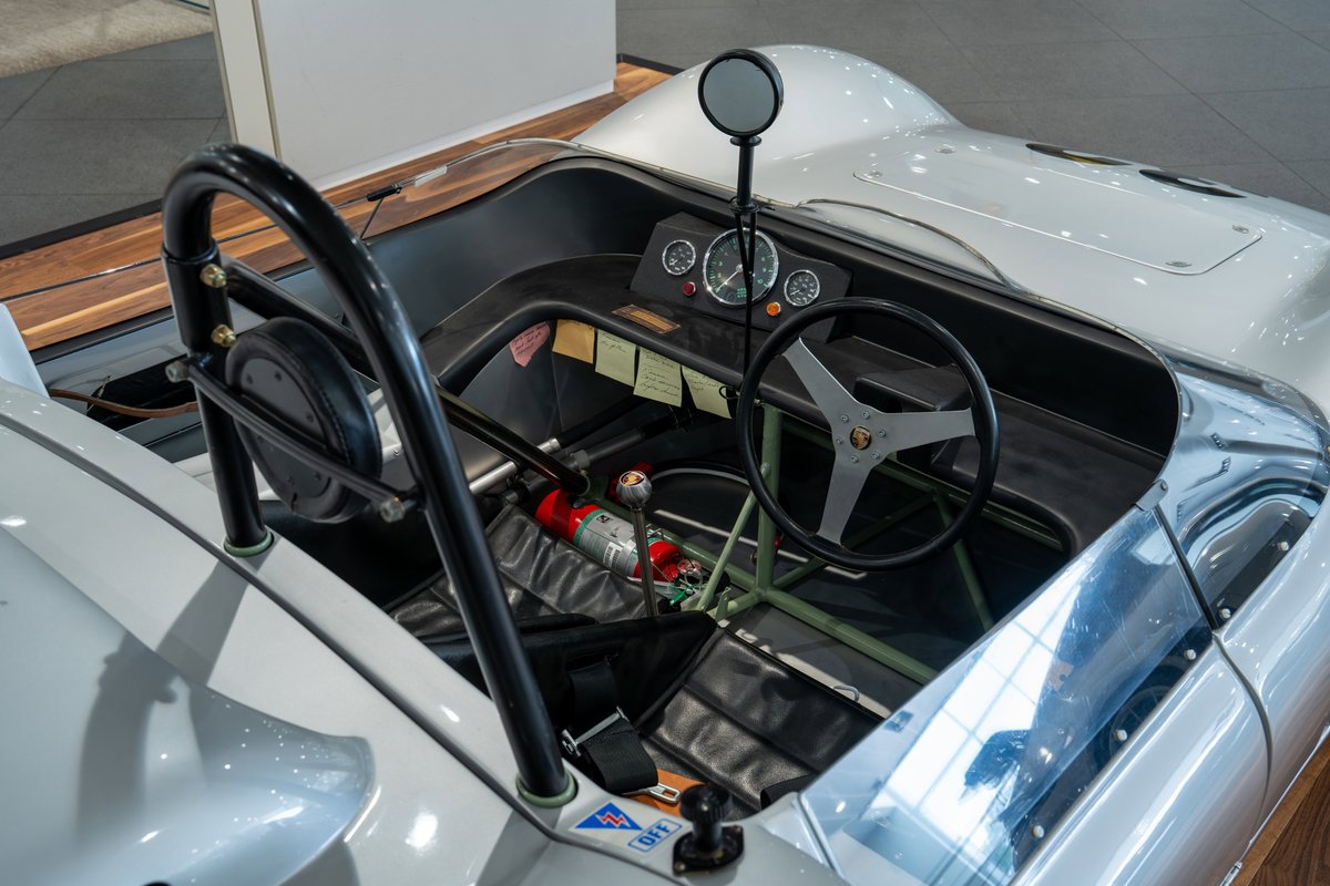 Close-up interior of a 1964 Elva Porsche 4-cam race car, showing the steering wheel, dash, and roll bar.