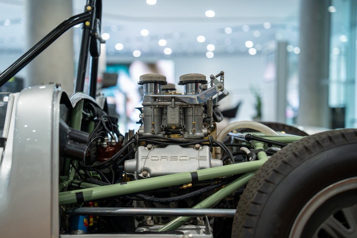 Close-up of a 1964 Elva Porsche 4-cam engine. Silver body panels, dual carburetors.