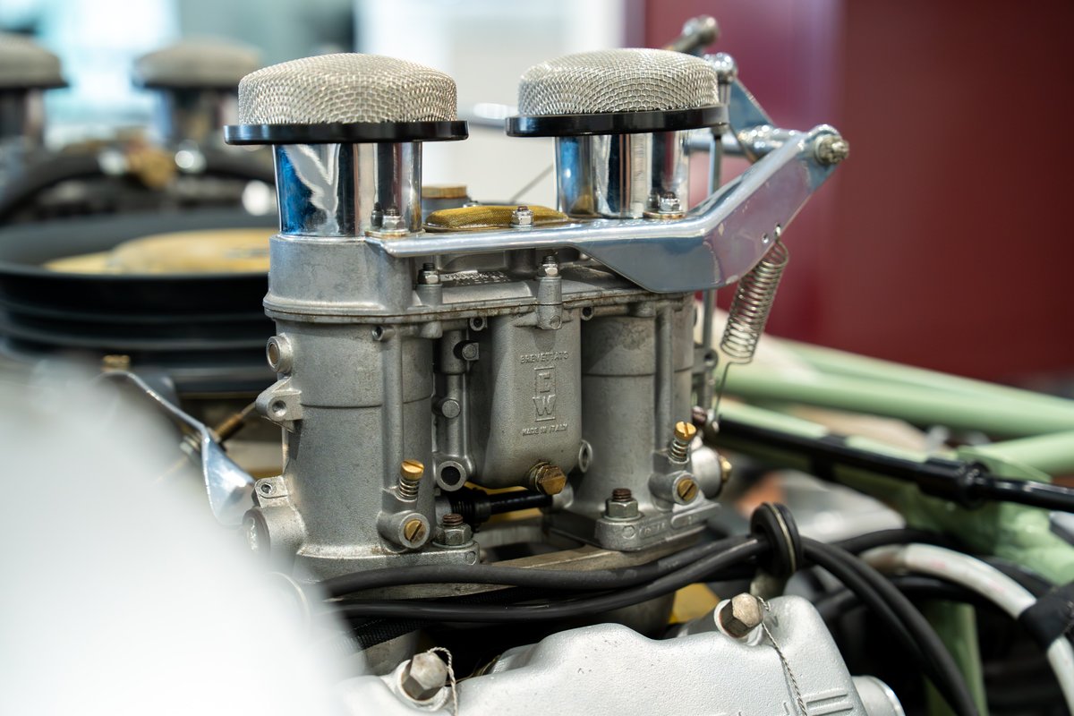 Close-up of a vintage Elva Porsche 4-cam engine with Weber carburetors and chrome air filters.