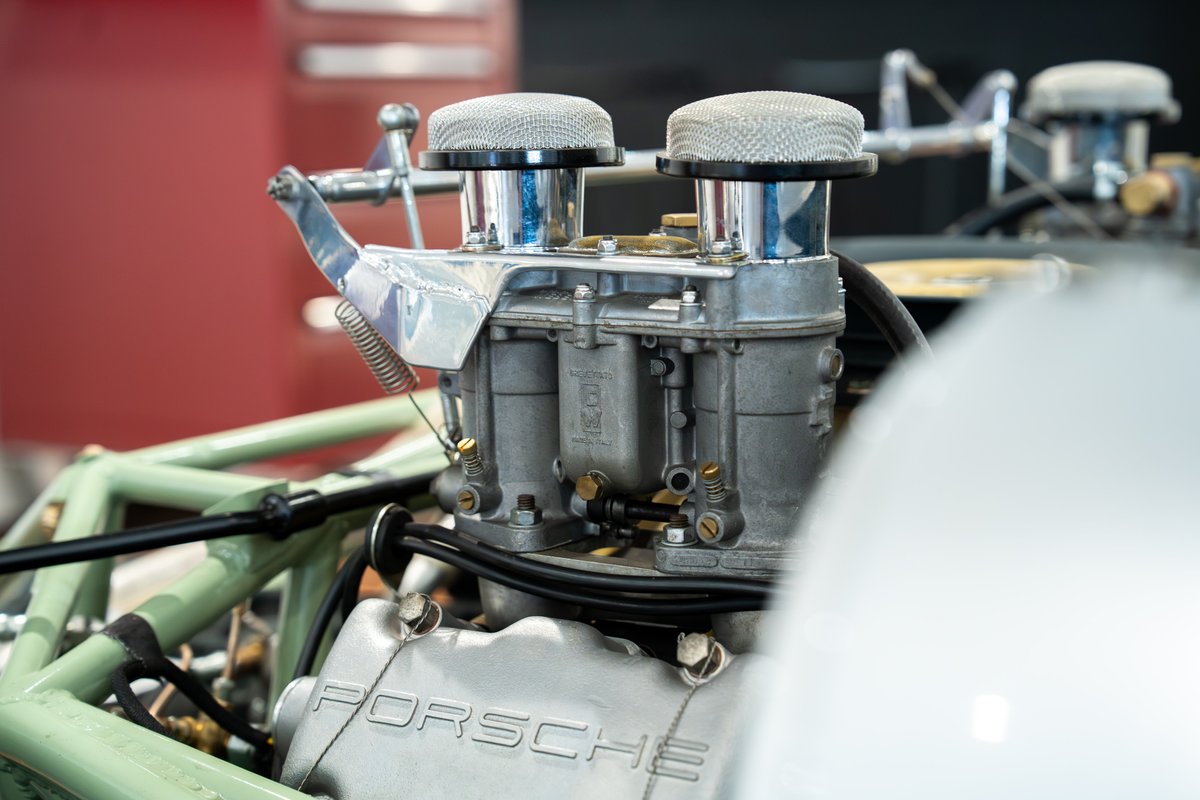 Close-up of a vintage 1964 Elva Porsche 4-cam engine with dual carburetors and air filters.