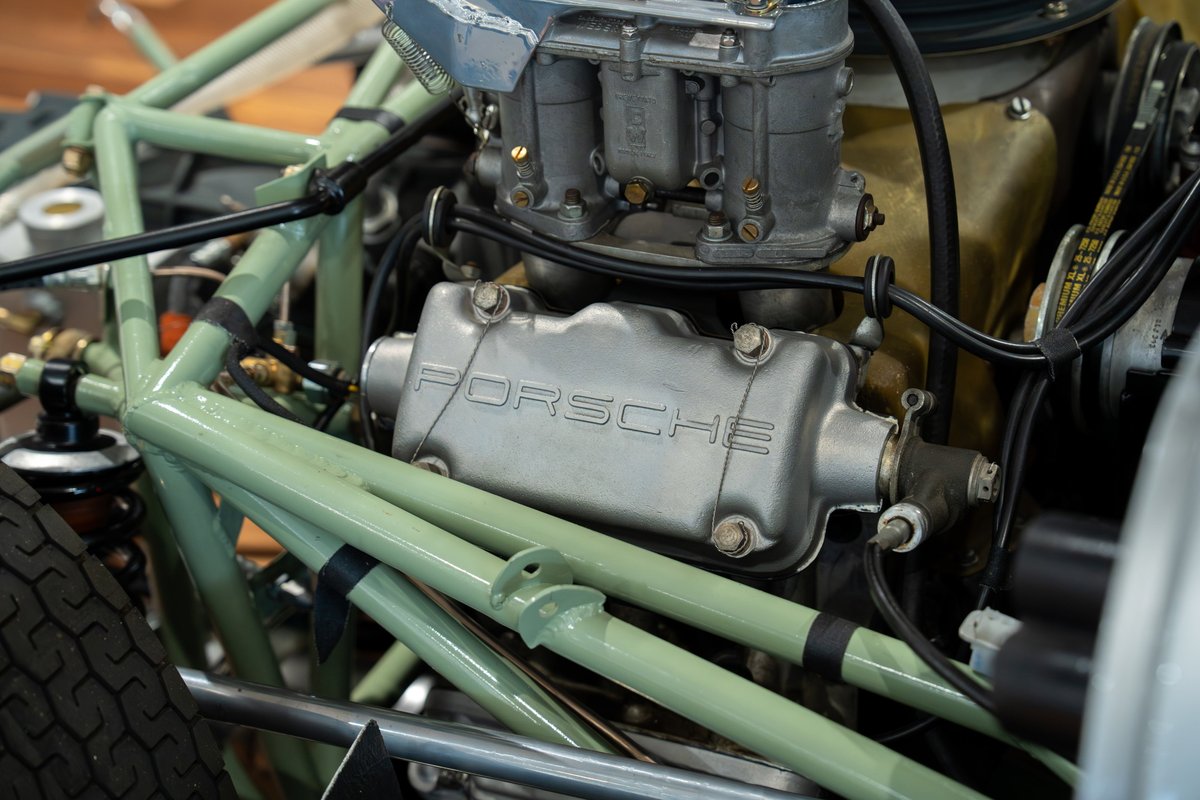 Close-up of the Porsche 4-cam engine in a vintage Elva race car with green chassis tubing.