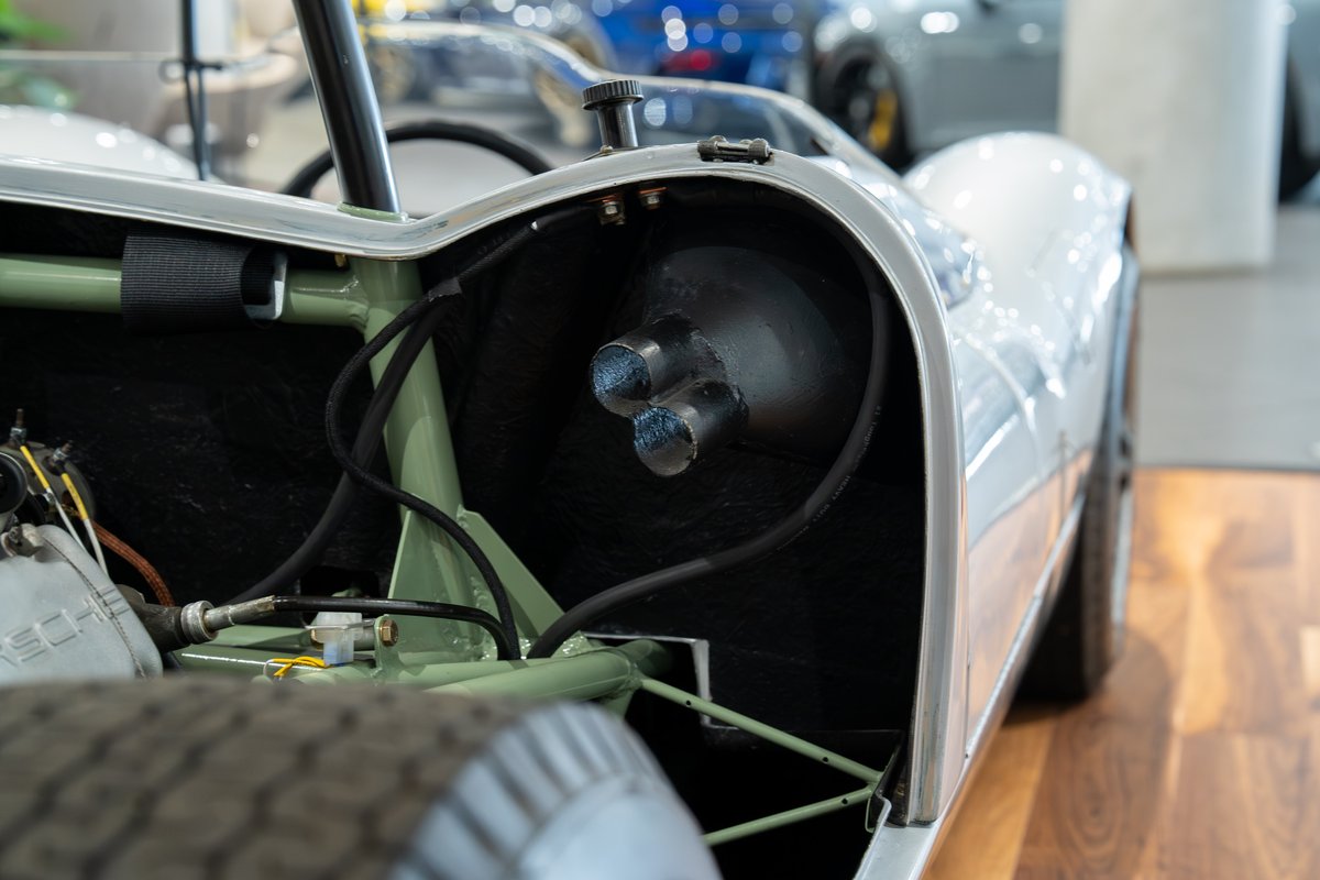 Close-up of a vintage Elva Porsche 4-cam's exhaust system, showcasing triple exhaust tips.