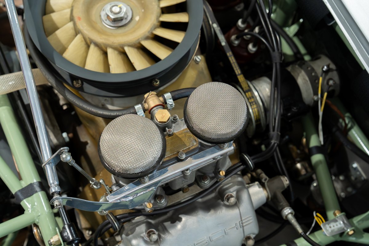 Close-up of a 1964 Elva Porsche 4-cam engine with dual carburetors and cooling fan.