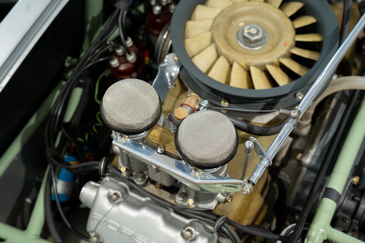 Close-up of a 1964 Elva Porsche 4-Cam engine, featuring dual carburetors with mesh air filters and cooling fan.