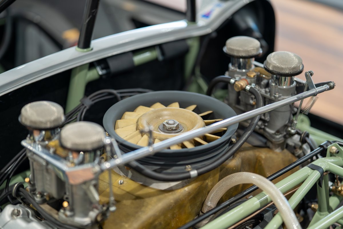 Close up of the engine bay of a 1964 Elva Porsche 4-cam, showing twin carburetors and cooling fan.