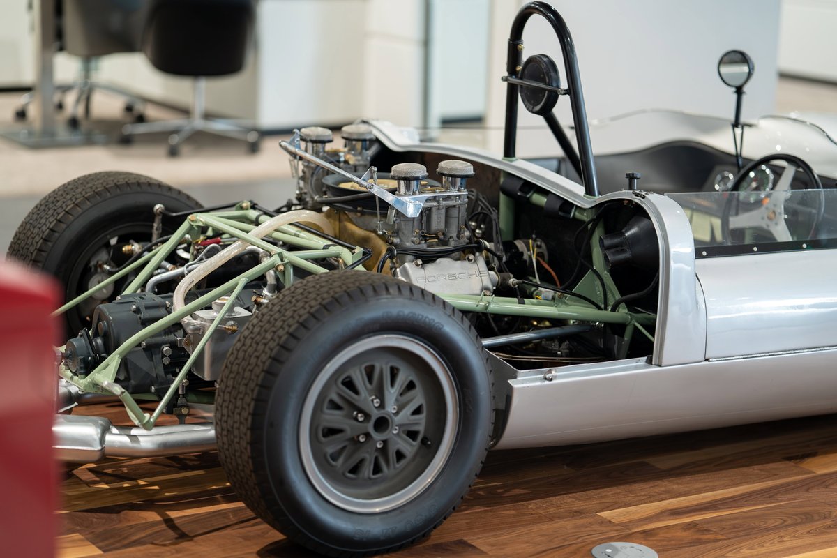 1964 Elva Porsche 4-Cam race car with exposed engine, gray alloy rims, and roll hoop.