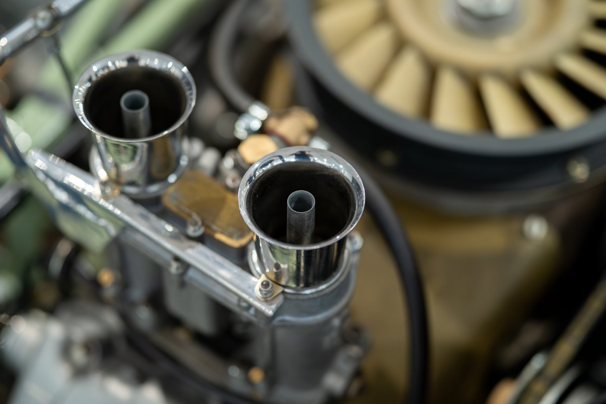 Close-up of dual chrome intake trumpets on a 1964 Elva Porsche 4-cam engine.