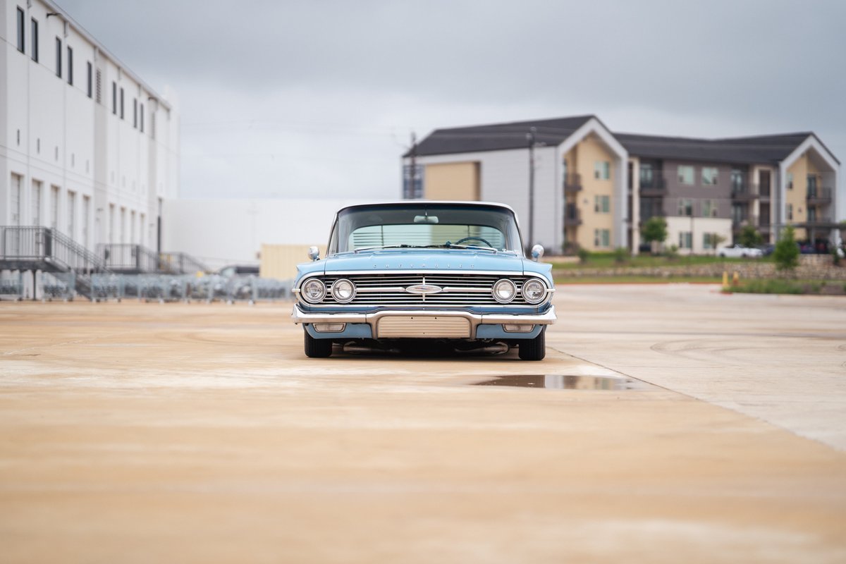 Front view of a light blue 1963 Chevrolet Impala lowrider with chrome trim and classic rims.