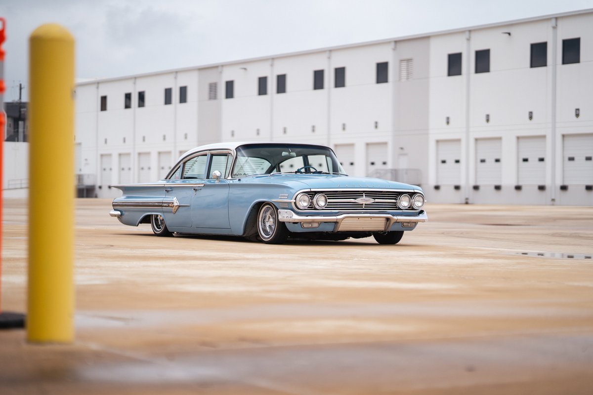 1960 blue Chevrolet Impala lowrider with chrome rims and white roof trim.