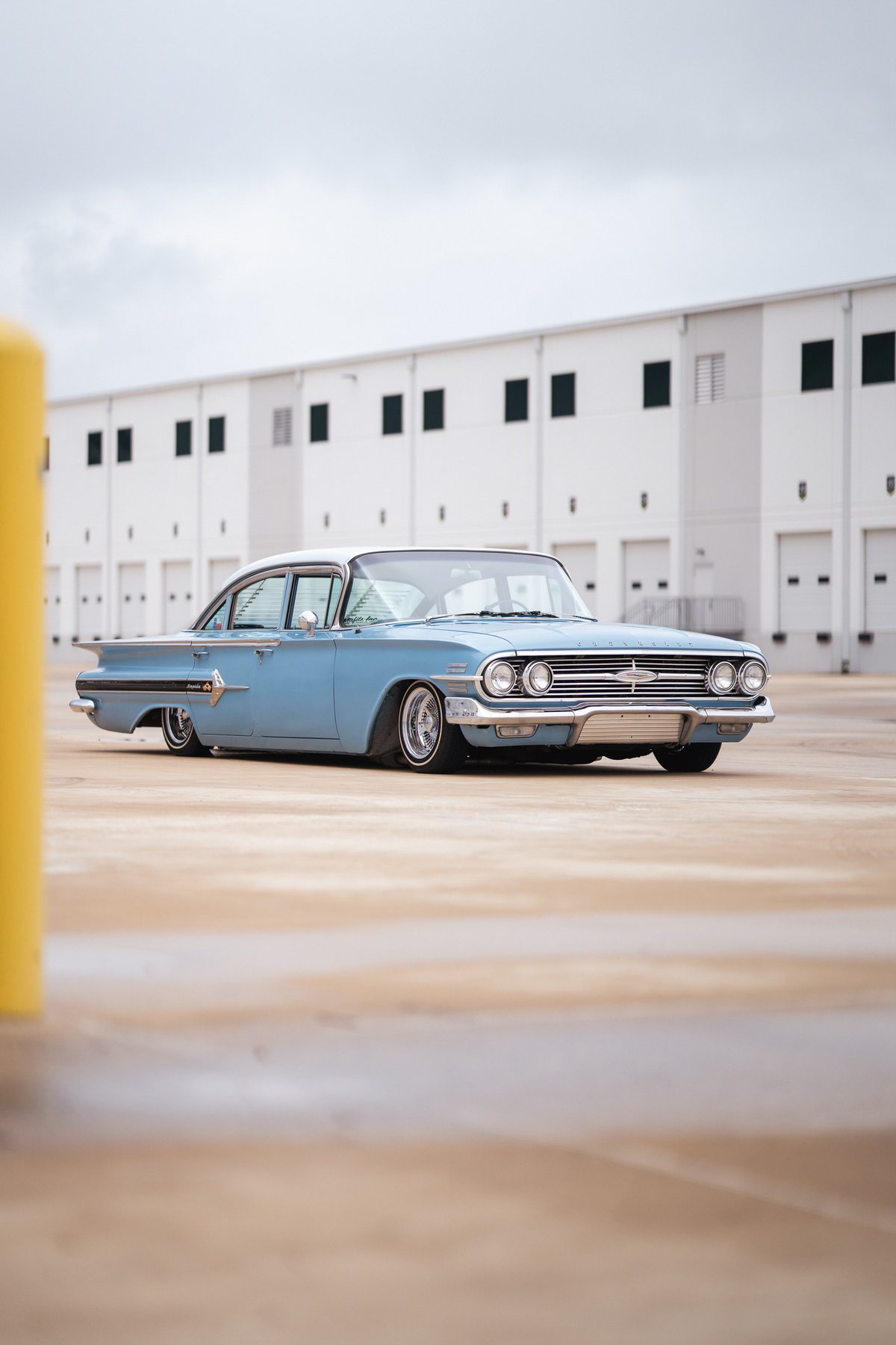 1960 blue Chevrolet Impala lowrider with chrome rims and white-wall tires, custom trim.