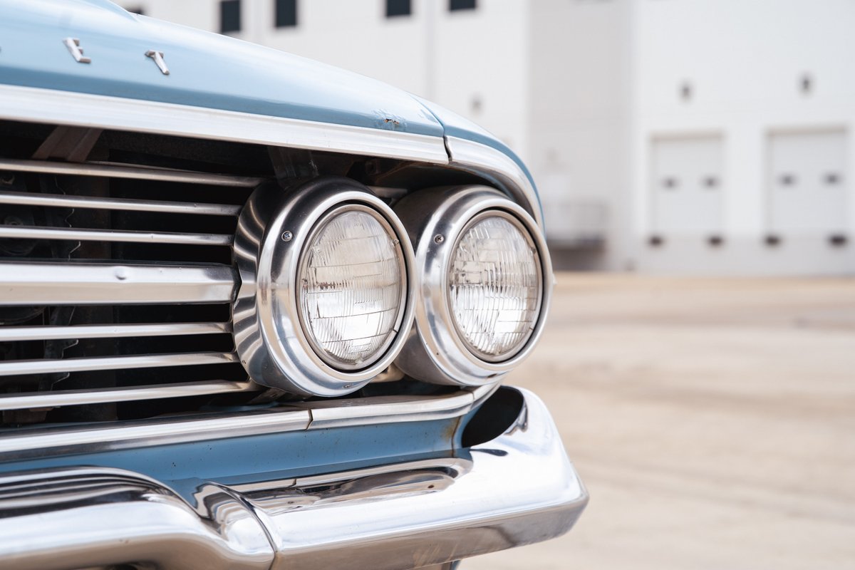 Front view of a blue 1963 Chevrolet Impala's dual chrome headlights and grille.