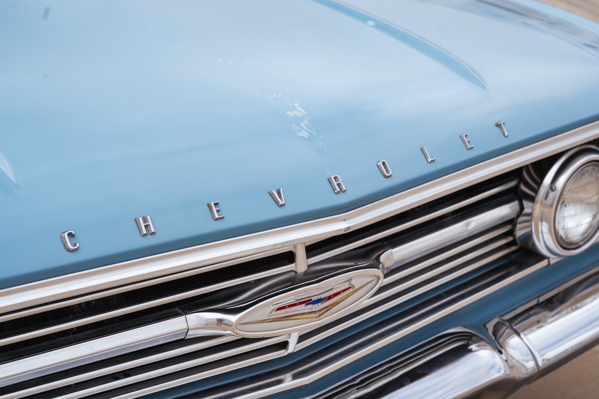 Close up on the blue 1963 Chevrolet Impala hood emblem and chrome grill.