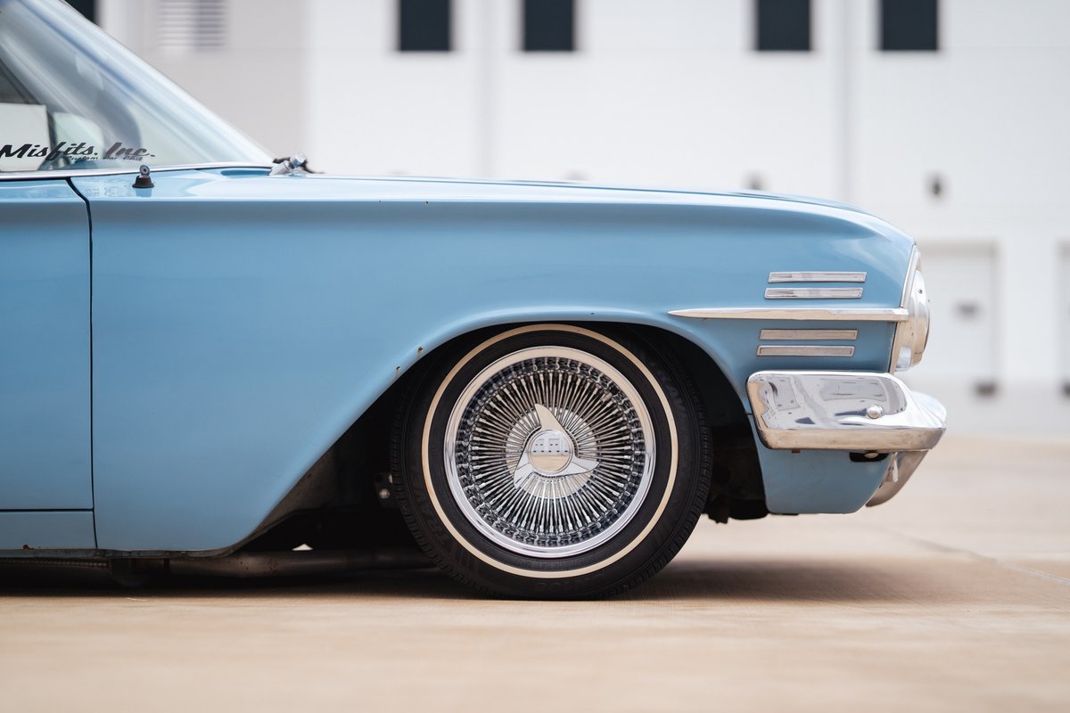 Lowrider 1963 Chevy Impala in blue with chrome wire rims and whitewall tires.