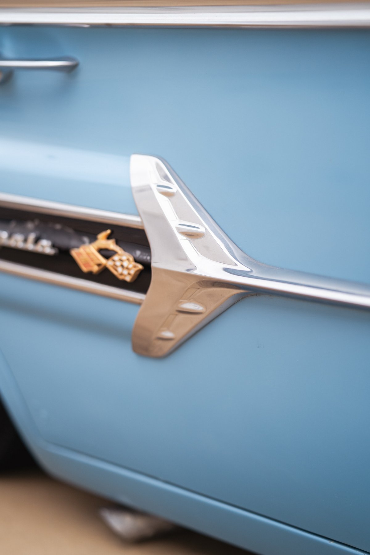 1963 blue Chevrolet Impala detail showing chrome trim and a gold Impala emblem.
