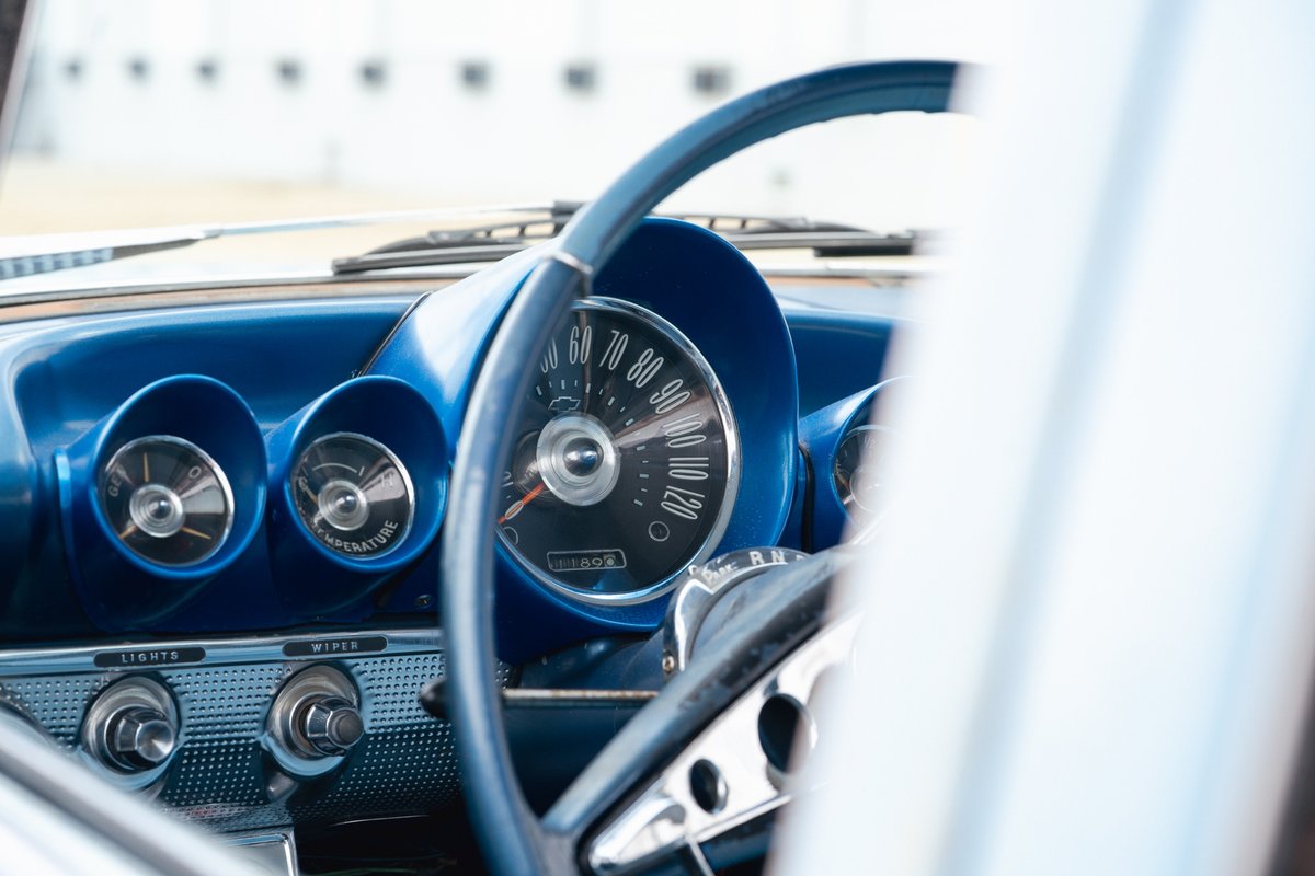 Close-up of a blue 1963 Chevrolet Impala dashboard with vintage gauges and steering wheel.