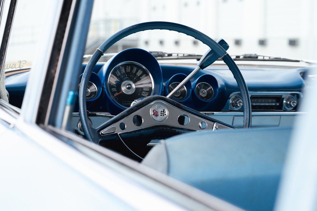 Close-up of a 1963 blue Chevrolet Impala lowrider interior, featuring a turquoise steering wheel and dashboard trim.
